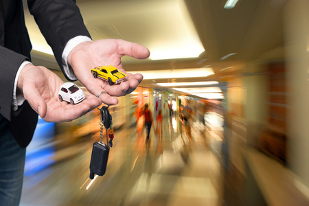 Closeup of businessman in black suit holding small car modelsの写真素材