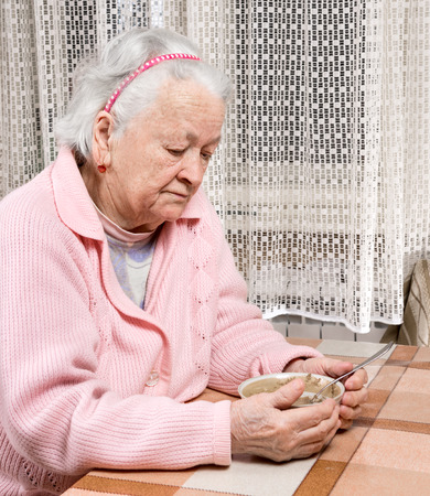Old sad woman eating at homeの写真素材