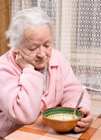 Old sad woman eating at homeの写真素材