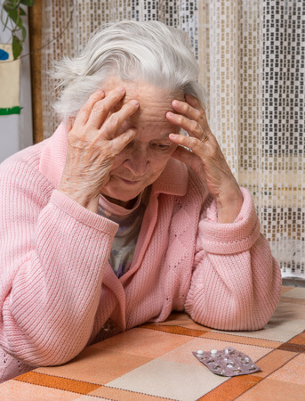 Old sad woman with pills at home.  Worried about  having to take too many pillsの写真素材