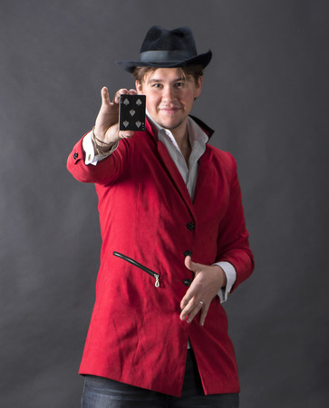 Young magician in hat with cards on a dark backgrounsの写真素材