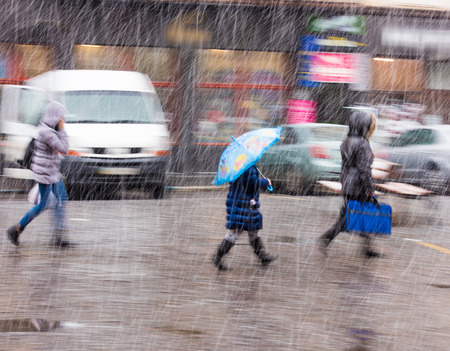 People walking down the street in a snowy winter day in motion blur