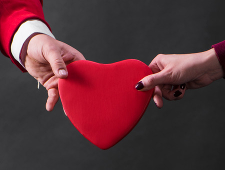 Close up of woman and man hands with heart on a dark backgroundの写真素材