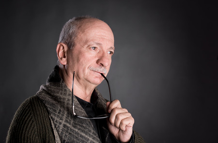 Portrait of thoughtful senior man on a dark backgroundの写真素材