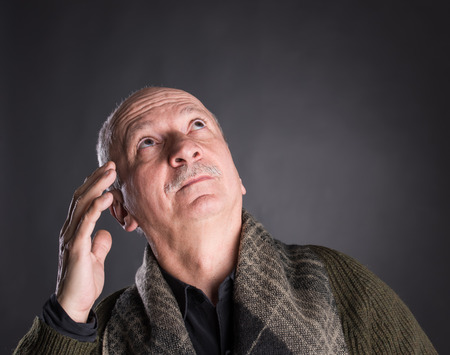 Portrait of thoughtful senior man on a dark backgroundの写真素材