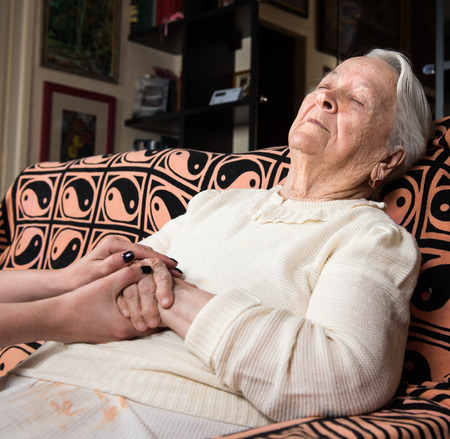 Caring hands holding old lady's hands at homeの写真素材