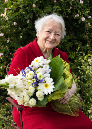 Old woman with a bunch of flowers on nature backgroundの写真素材