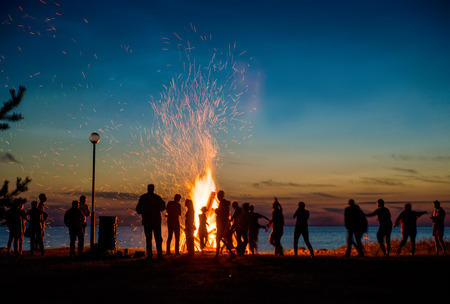 People resting near big bonfire outdoor at nightの写真素材
