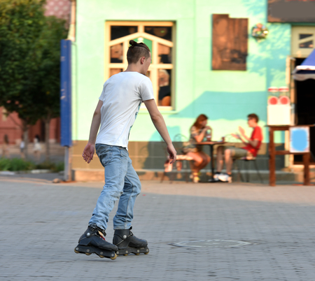 Yong man practicing rollerblading in town in motion blur