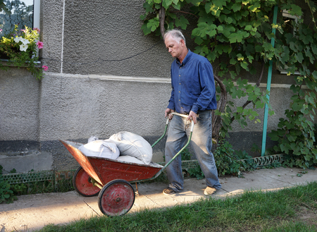 Man with barrow full of cement bags in the gardenの写真素材
