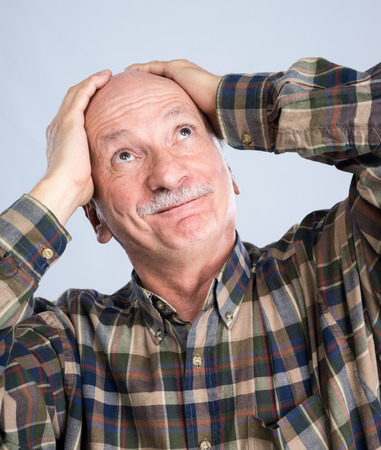 Smiling surprised senior man on a light grey backgroundの写真素材