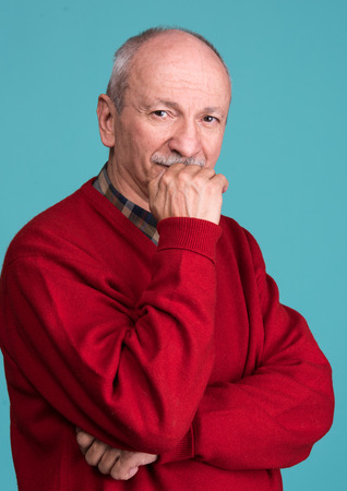 Portrait of a senior smiling man on a blue backgroundの写真素材