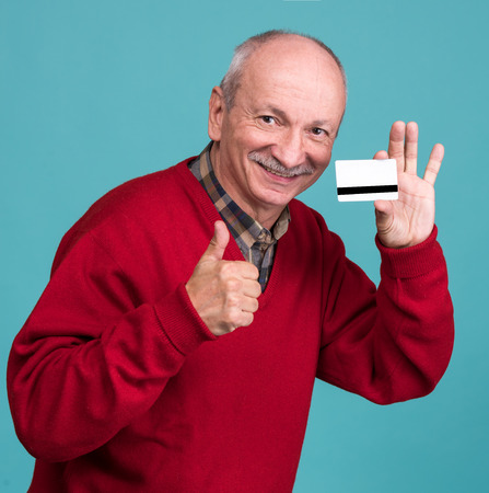 Senior man with credit card on a blue background