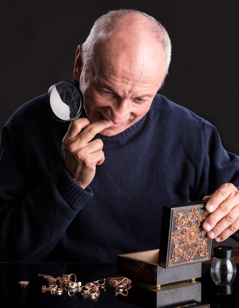 Senior jeweler with  magnifying glass on a dark backgroundの写真素材
