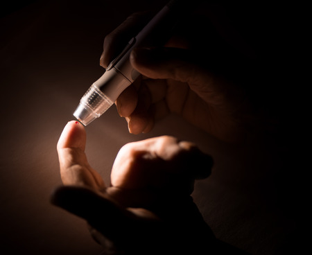 Close up image of elderly woman with glucometer checking blood sugar level