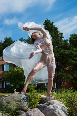 Young nude woman posing in polyethylene film on the beachの写真素材