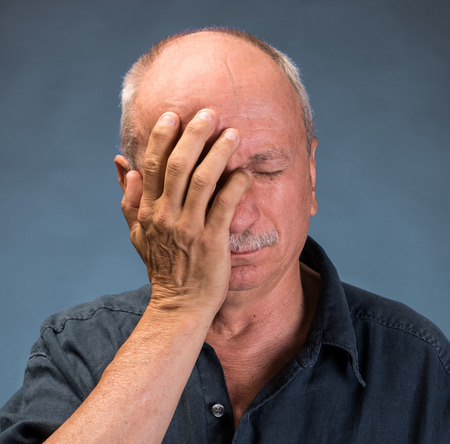 Elderly man suffering from a headache on a dark backgroundの写真素材