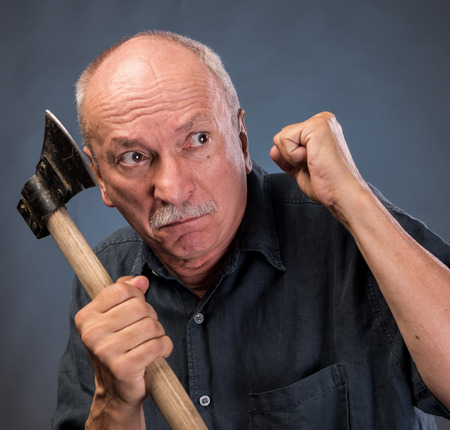 Angry elderly man with an ax on a dark backgroundの写真素材