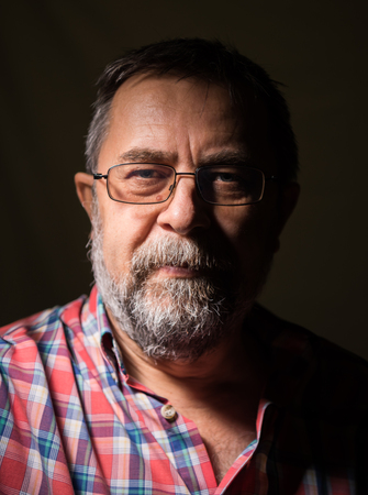 Beard elderly man in glasses posing on a dark backgroundの写真素材