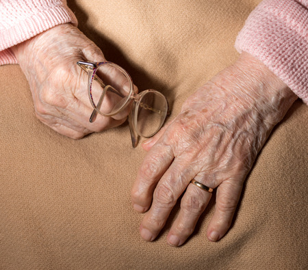Close-up of old woman's hands holding glassesの写真素材