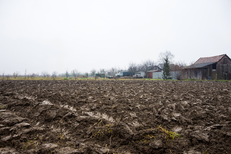 Ploughed field ready for new crops. Rich deep brown soil.Rainy autumn dayの写真素材
