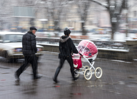 Family with stroller on zebra crossing in motion blur in a snowy dayの写真素材