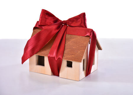 Small model of a wooden house tied with a bow isolated on white . Eco houseの写真素材