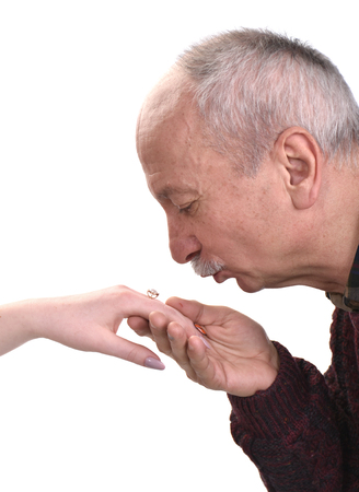 Senior man kissing woman's hand on a white backgroundの写真素材
