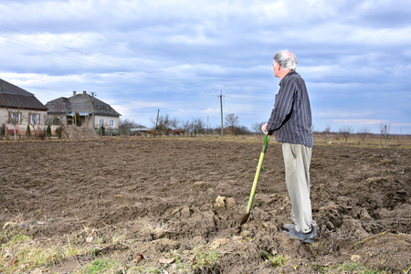 Farmer standing with a shovel on the field. Spring time. Beginning of spring work on the fieldの写真素材