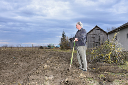 Farmer standing with a shovel on the field. Spring time. Beginning of spring work on the fieldの写真素材