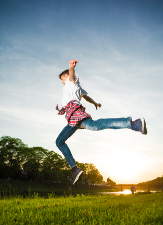 Sport and leisure concept. Teenager boy jumping  in the park at sunset. Summer sunny day