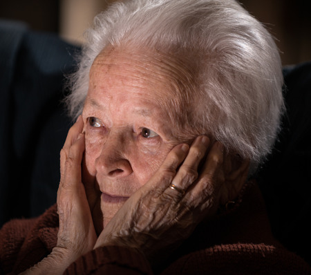 Portrait of old gray-haired sad woman at home. Sick depressed old womanの写真素材