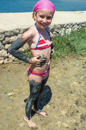 Small girl applying black healing clay at the spa resortの写真素材