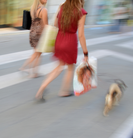 Women with shopping bags walking with a dog in motion blurの写真素材