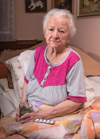 Healthcare, medical concept. Old gray-haired sick woman taking medicine at home.の写真素材
