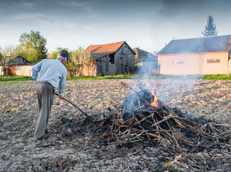 Agricultural concept. Work in the garden. Farmer burning dried branches. Spring timeの写真素材