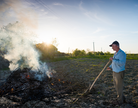 Agricultural concept. Work in the garden. Farmer burning dried branches. Spring timeの写真素材