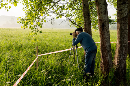 Travel photographer taking landscape pictures on the fieldの写真素材
