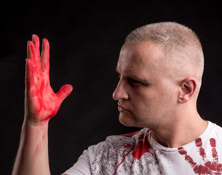 Portrait of  man with bloody hand posing on a black backgroundの写真素材