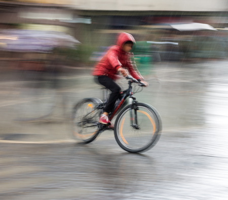 Cyclist on the city roadway on a rainy day in motion blurの写真素材