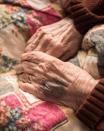 Close up of old wrinkled woman's hands. Bruise from the injection on the arm