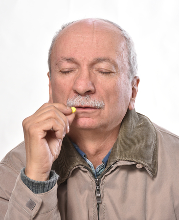 Senior man wants to take a pill on a white background