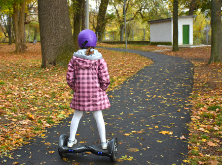Girl in helmet riding on the hoverboard in the park in autumn dayの写真素材