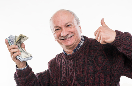 Senior man expressing happiness while posing with dollar and euro bills on a white backgroundの写真素材