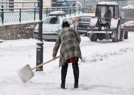 Woman shoveling winter snow in the city street. Intentional motion blurの写真素材