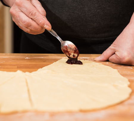 Producing classic croissants at home. Woman rolling dough into rolls for further bakingの写真素材