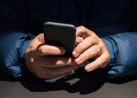 Close up of senior mans hands using mobile phone at the cafeの写真素材