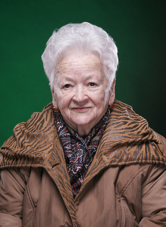 Portrait of smiling beautiful old woman on a green background