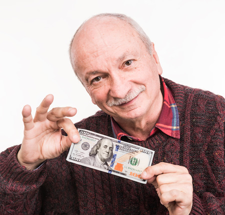 Senior man holding a stack of money. Portrait of an excited old businessman. Happy old man holding dollar banknotes over white backgroundの写真素材