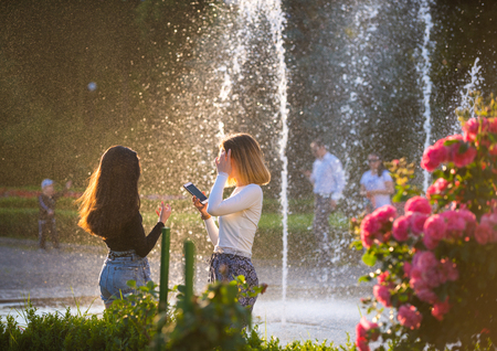 UZHGOROD, UKRAINE - JUNE 6, 2019: Two teen girls standing near fountain and enjoying summer time  in Uzhhorod, Ukraineのeditorial素材